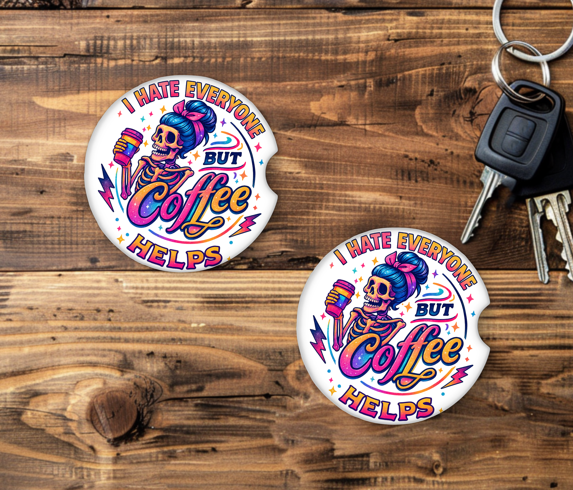 Two car coasters with a colorful skeleton design and text on a wooden surface with keys.