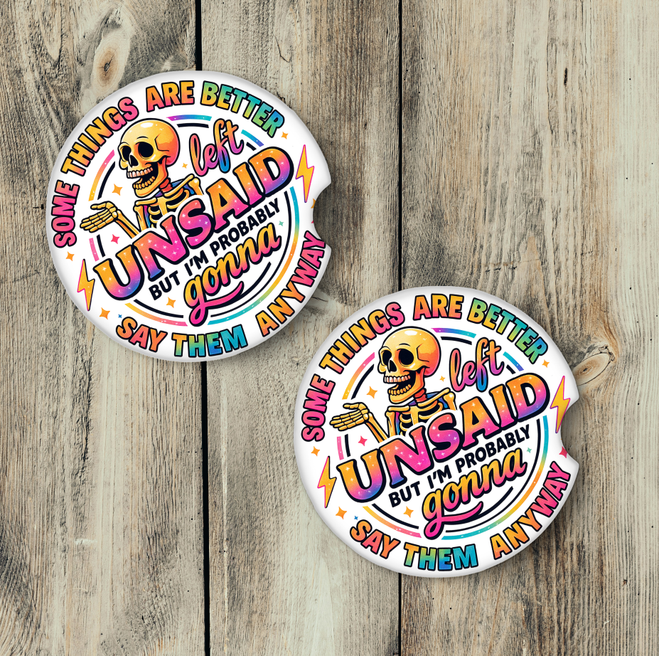 Two car coasters with colorful text and a skull design on a wooden surface.