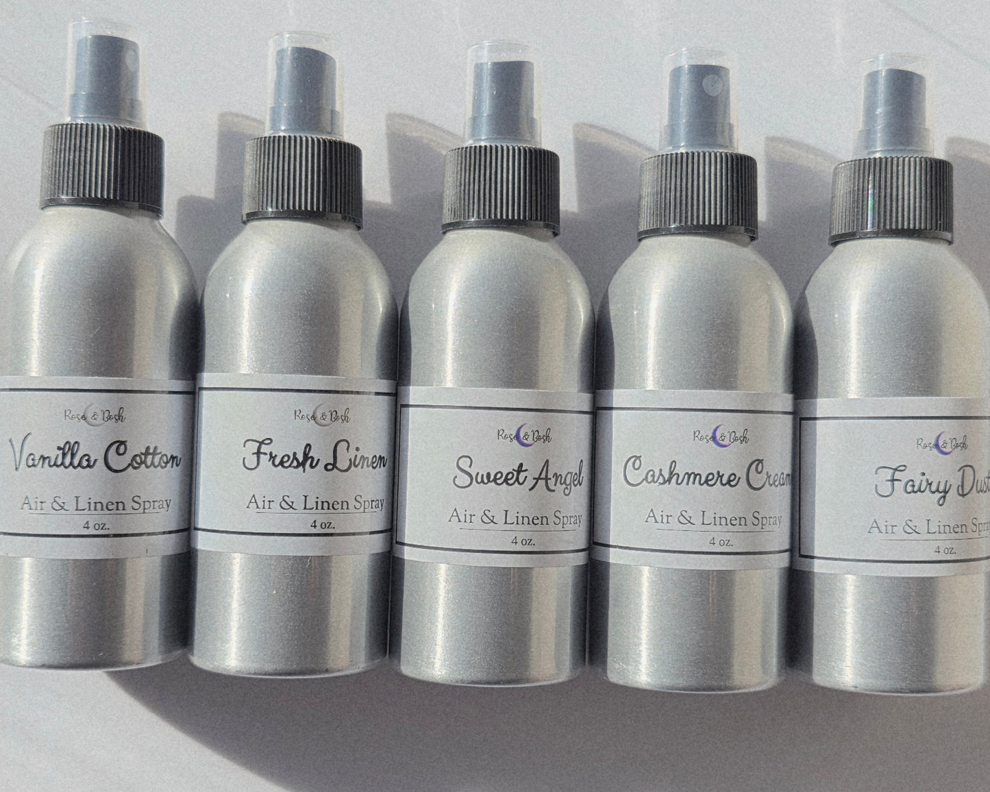Set of five silver air freshener bottles with labels on a light gray background